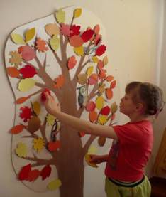 дети украшают дерево на стене